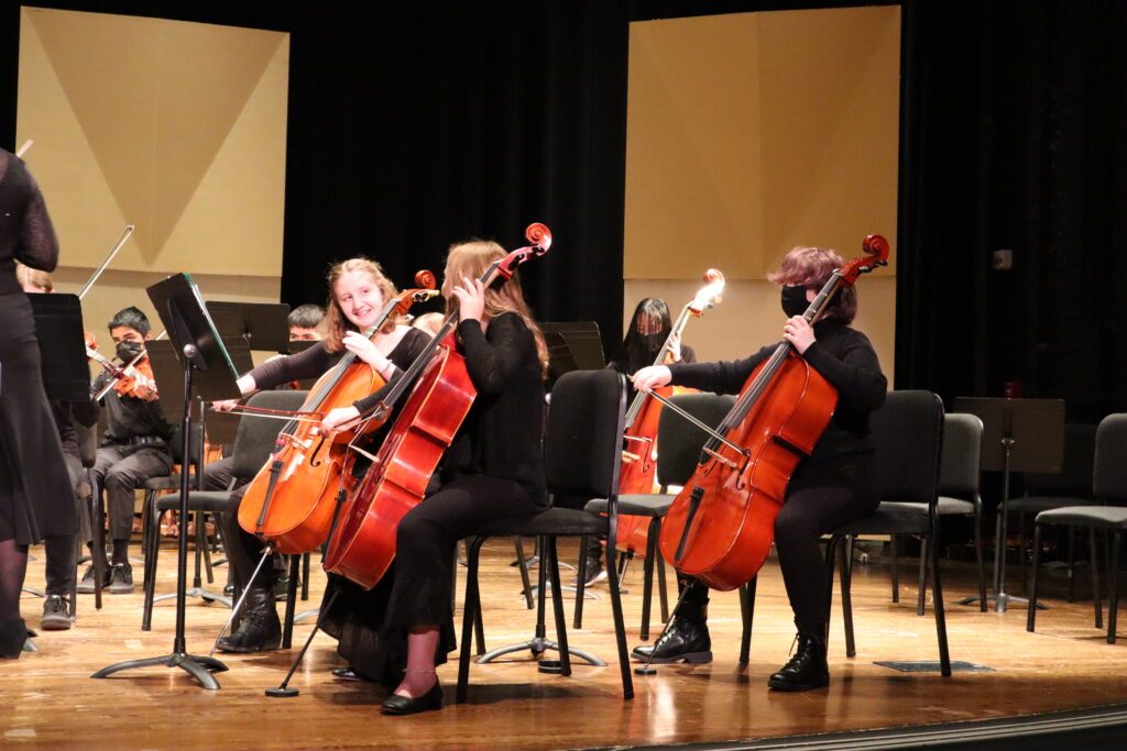 young female musicians playing cellos on a stage