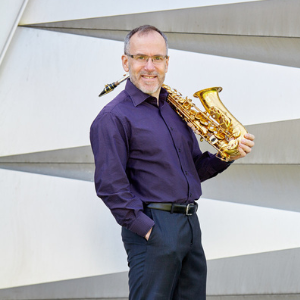 white male in purple shirt holding a saxophone
