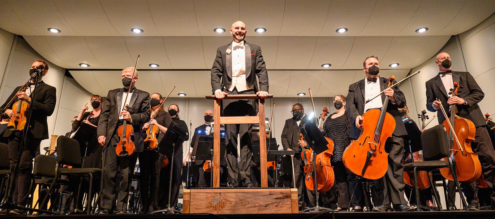 orchestra musicians and conductor in tuxedos