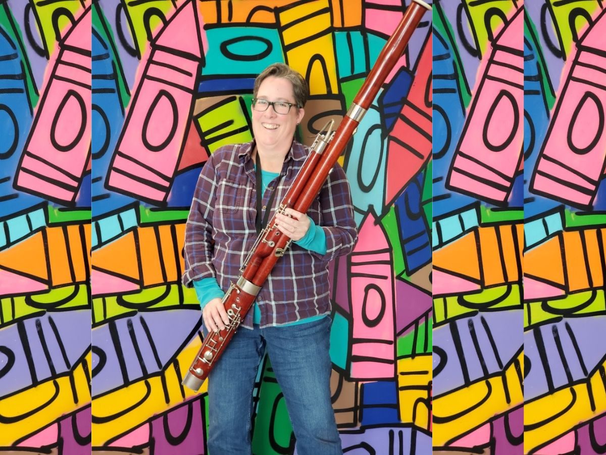 crayon colors mural with bassoon musician standing in front holding wooden bassoon wearing plaid shirt and blue jeans