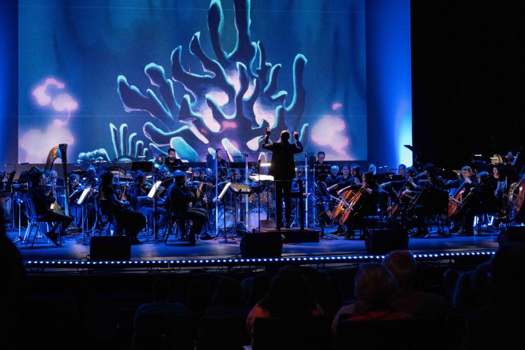 blue ocean cartoon background with orchestra and conductor playing instruments on stage