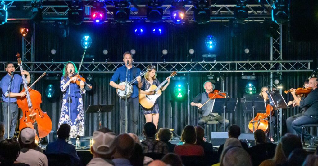 bluegrass quartet musicians and string quartet musicians performing on a blue lit stage